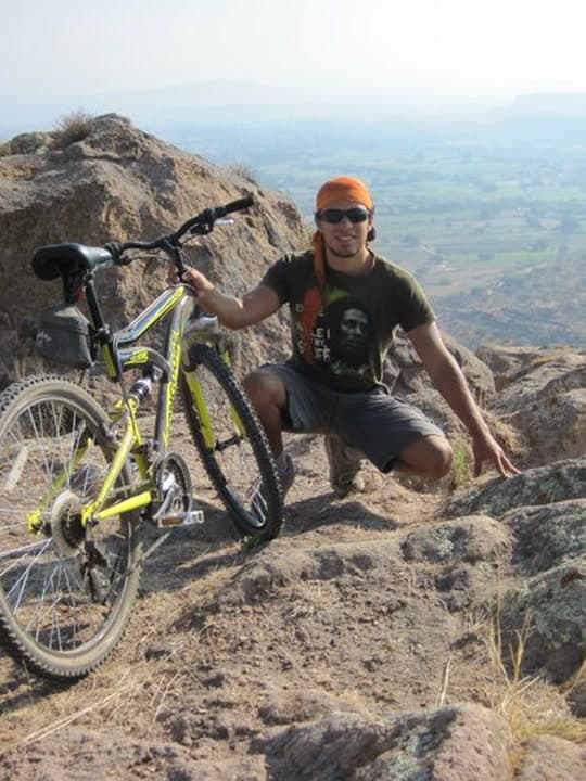 Crouched on a rocky summit next to a yellow mountain bike